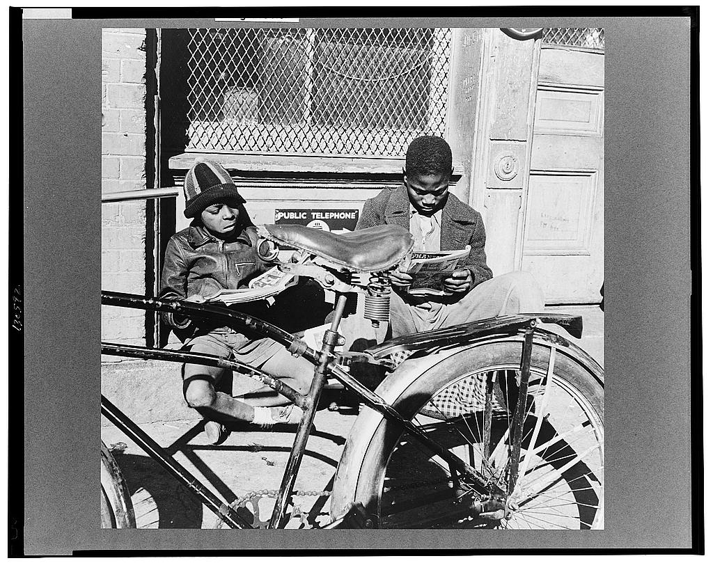 Black and white photograph by Gordon Parks. Washington, D.C. Two Negro boys reading the funnies on a doorstep.